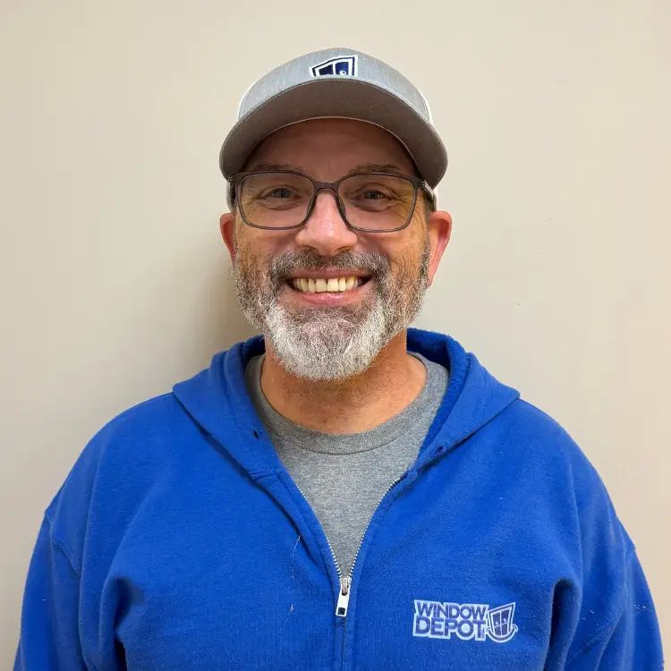 Smiling man with gray beard and glasses, wearing a gray cap and blue Window Depot hoodie, posed against a beige wall. - My Topp Home