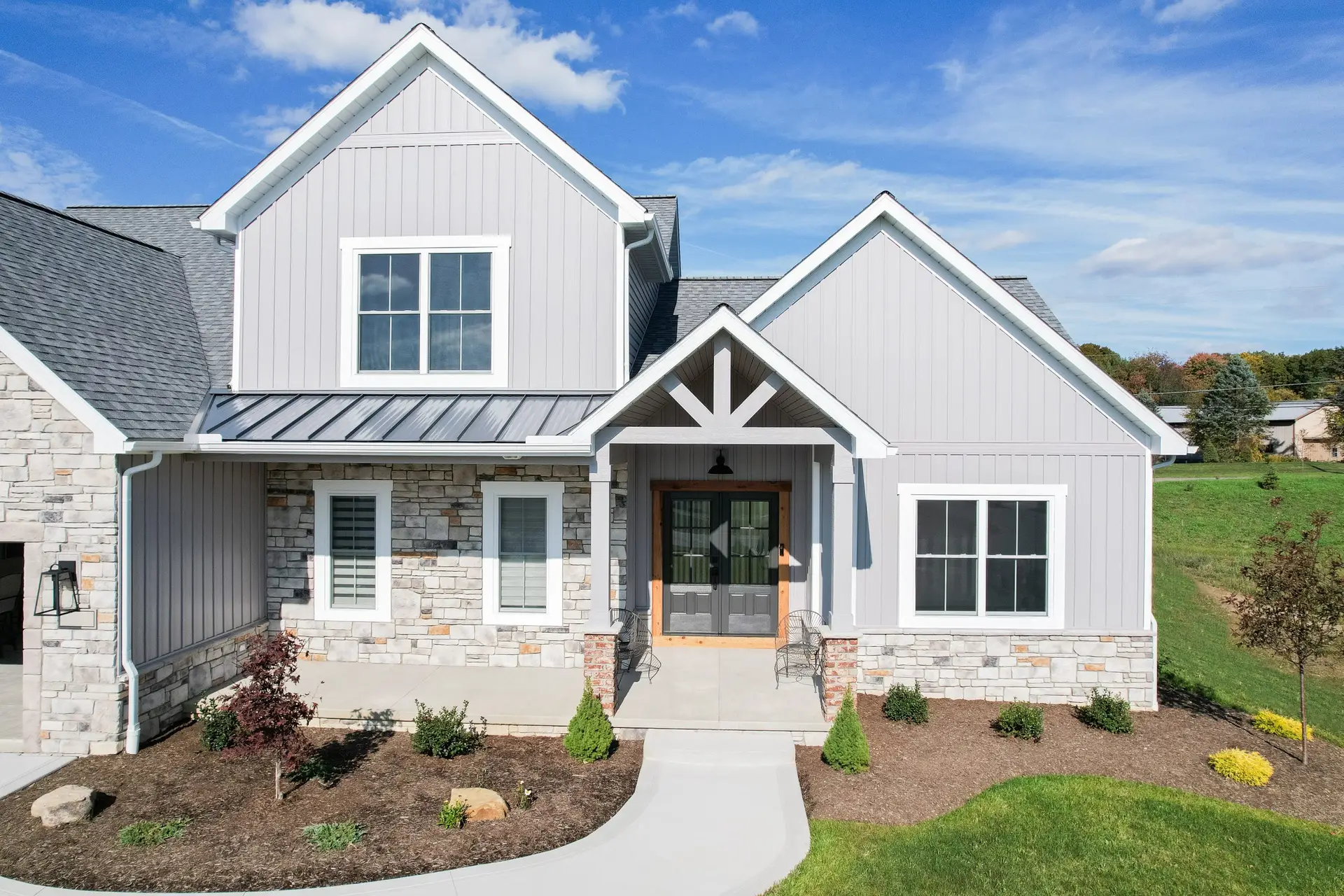 Front view of a modern gray house with stone accents, gabled roof, and a covered entryway. - My Topp Home